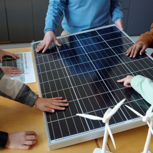 Group of people gathered around large solar panel, discussing its features and benefits with hands-on engagement, highlighting involvement in renewable energy education
