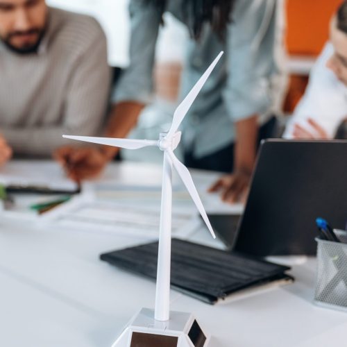 Green energy, model of wind turbine. People are working in the office together.