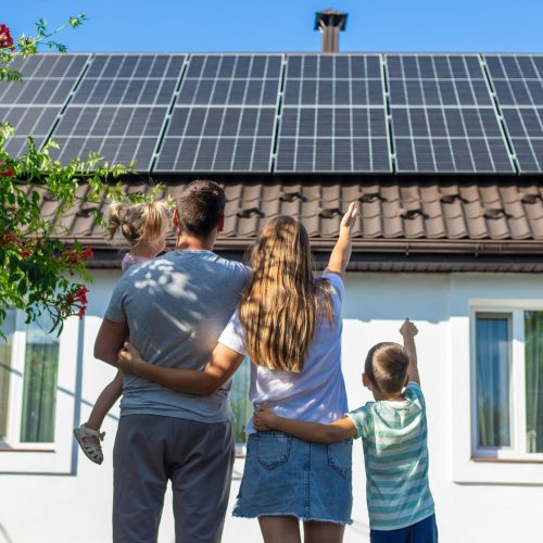 happy family on the background of a house with solar panels on the roof. Selective focus.
